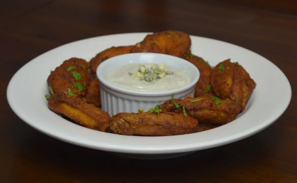 Prato com buffalo wings fritas e ramequim de molho de queijo azul no centro