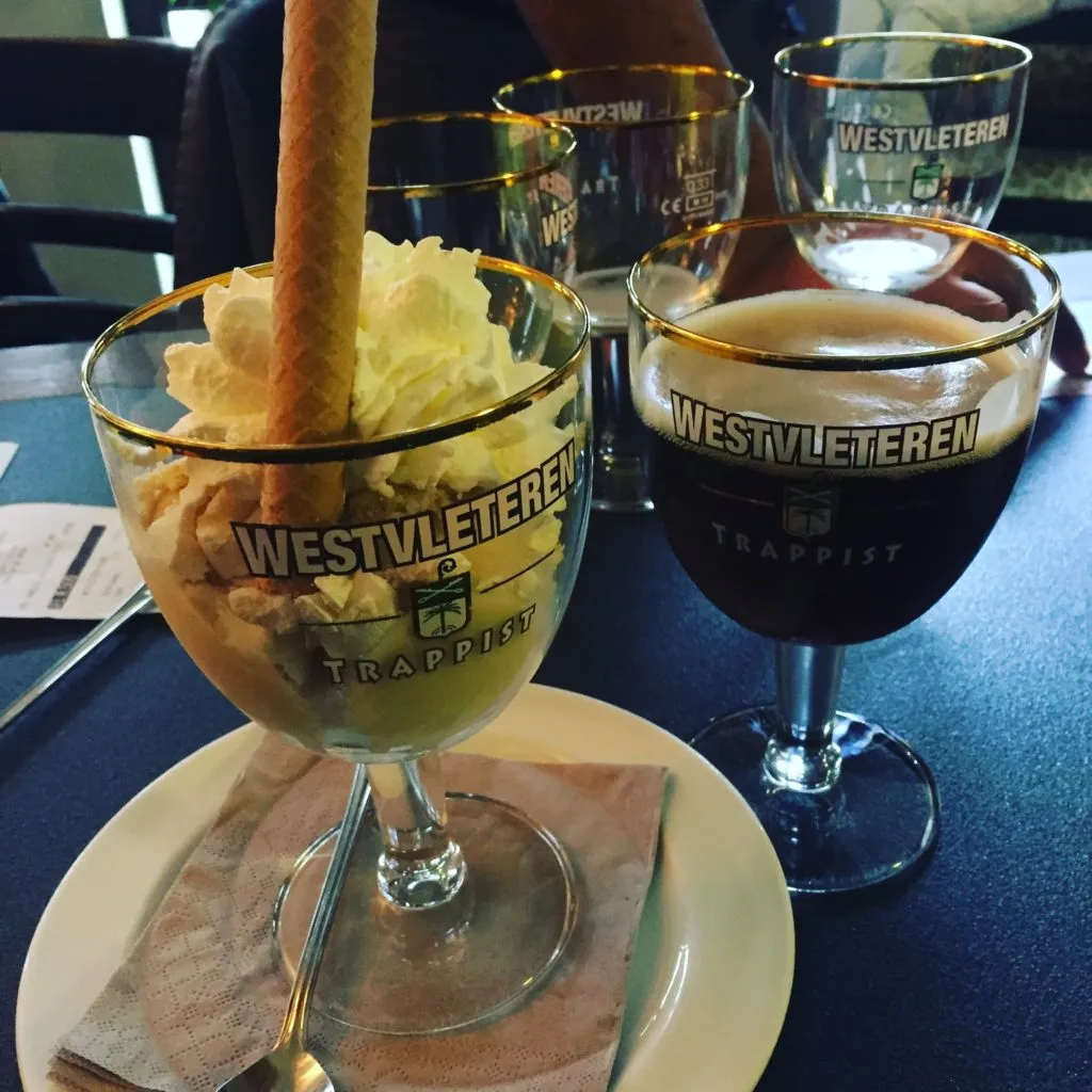 Taças Westvleteren: uma com sorvete e chantilly, outra com cerveja escura de espuma bege, sobre a mesa