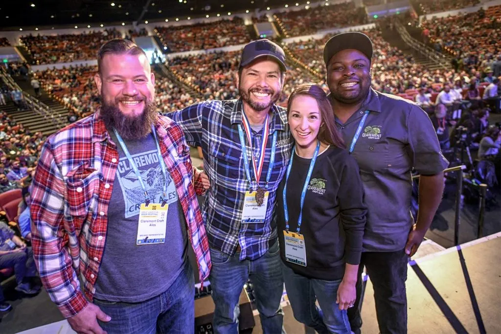 Quatro integrantes da cervejaria Claremont Craft Ales no palco do Great American Beer Festival, diante da plateia