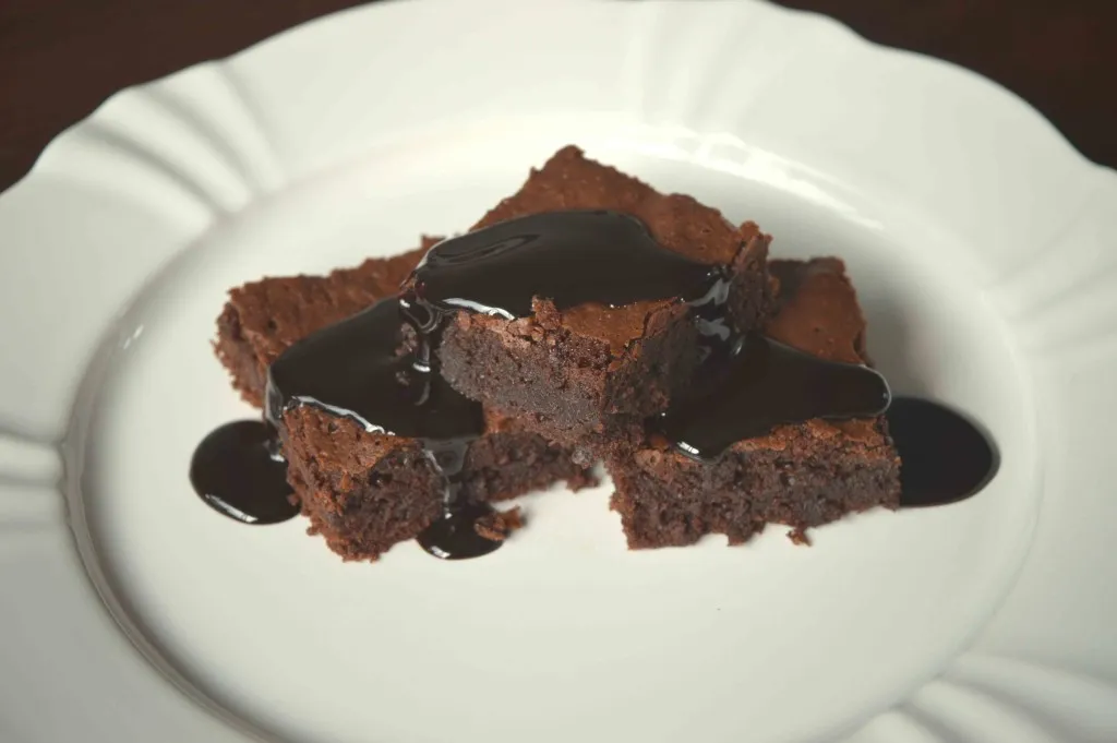 Brownies em prato branco cobertos com calda escura de cerveja Porter