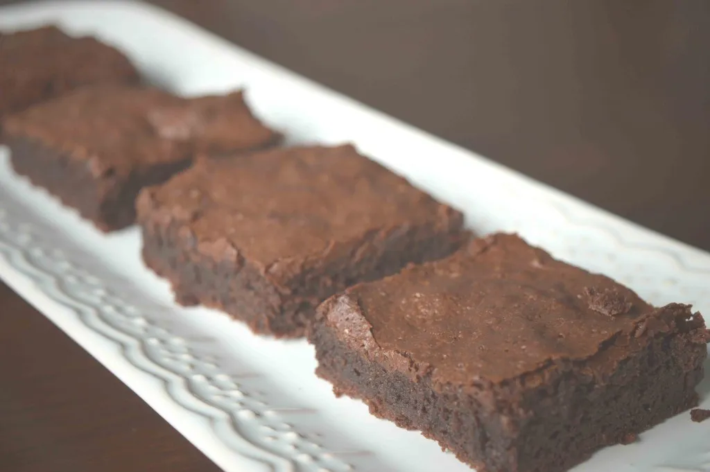 Quatro quadrados de brownie sem calda alinhados em travessa branca