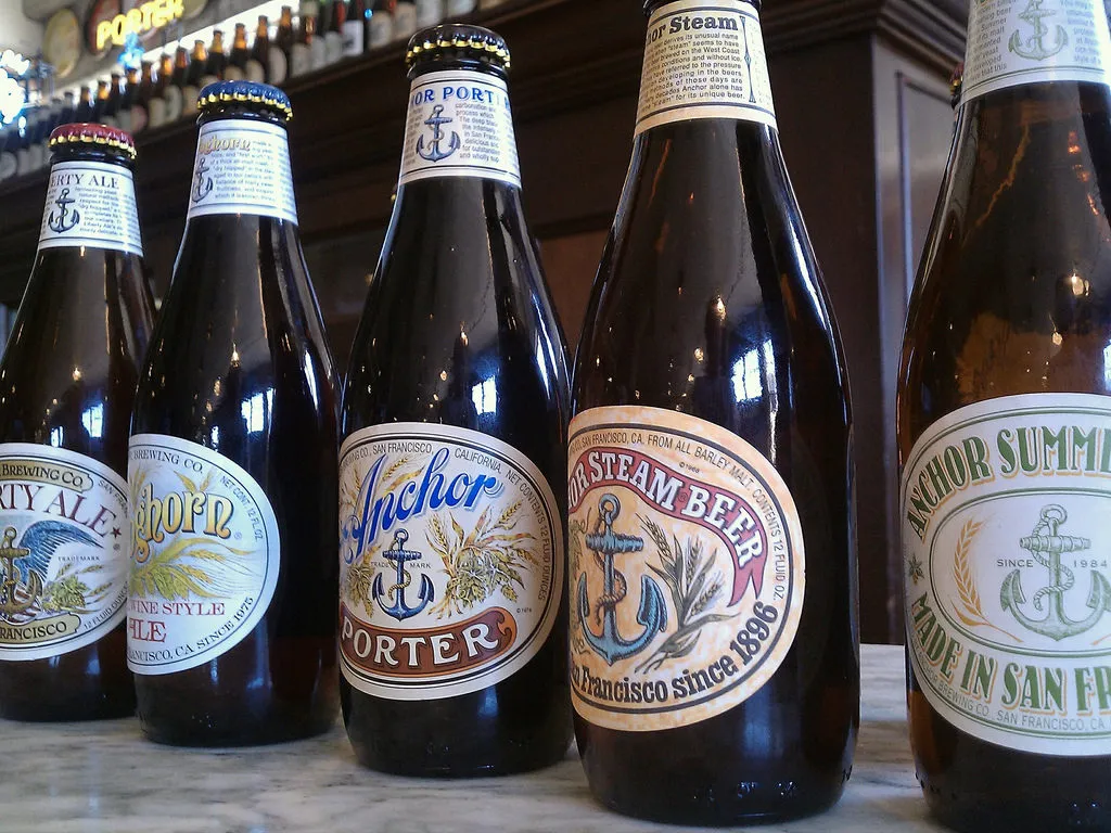 Garrafas de cerveja Anchor, incluindo Porter, Steam Beer e Summer, alinhadas sobre balcão