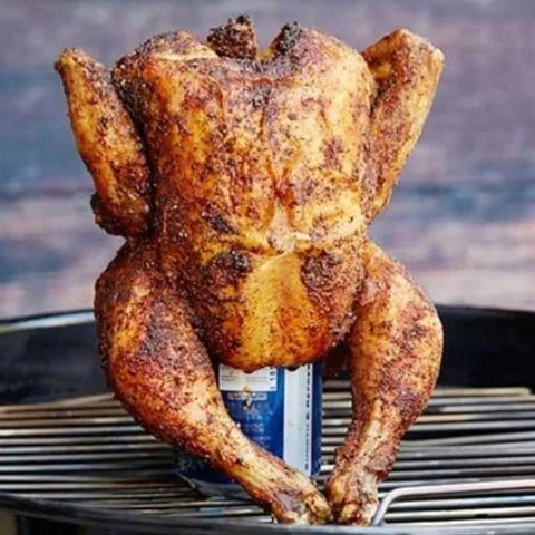 Frango assado inteiro, temperado, apoiado em lata de cerveja sobre a grelha
