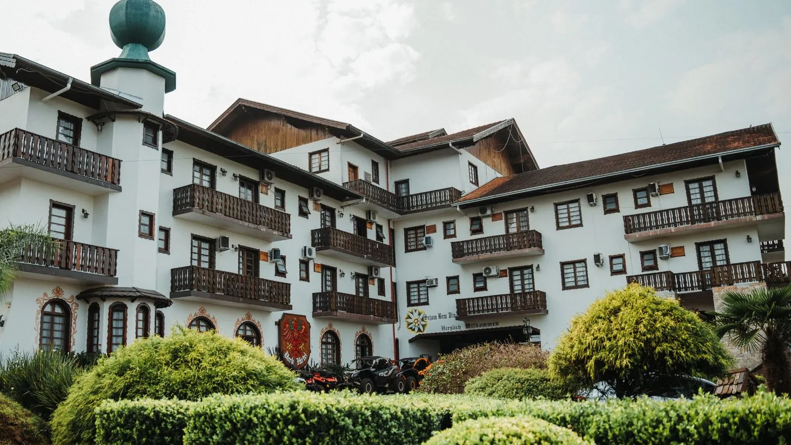 Fachada do Treze Tílias Park Hotel, hotel de estilo tirolês com sacadas de madeira e jardim