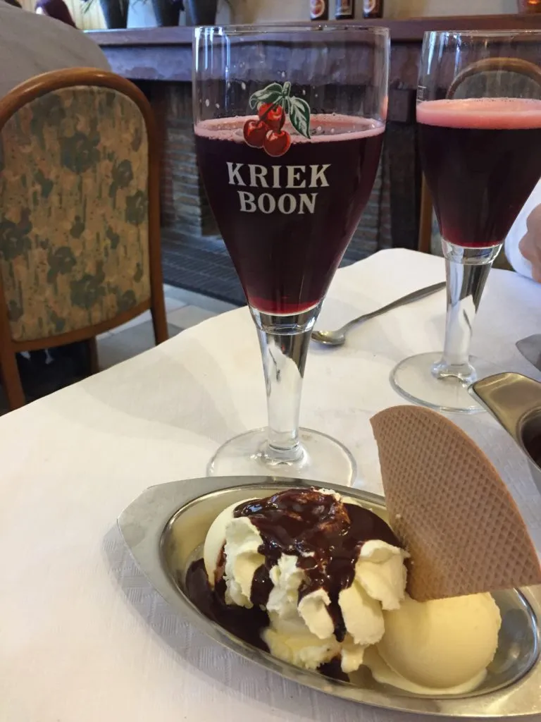 Duas taças Kriek Boon com cerveja de cereja avermelhada e, à frente, sorvete com calda de chocolate e waffle