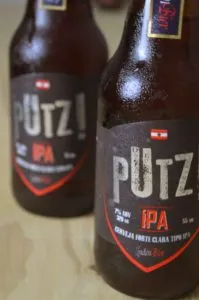 Duas garrafas da cerveja Putz IPA, da Linden Bier, com rótulo escuro e vermelho