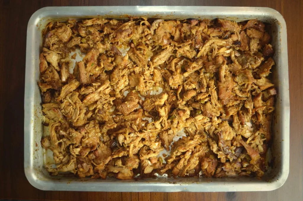 Pernil desfiado pronto em assadeira de metal, vista de cima
