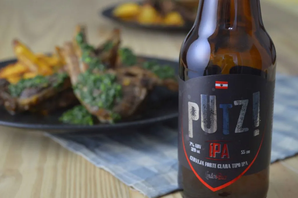 Garrafa da cerveja Putz! IPA, da LindenBier, com carré de cordeiro com molho verde e batatas fritas ao fundo