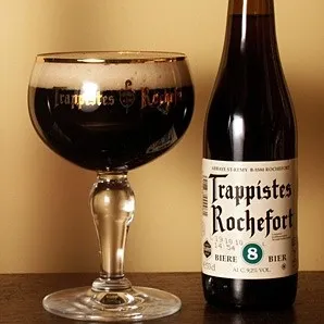 Garrafa de Trappistes Rochefort 8 ao lado de taça com cerveja escura e colarinho