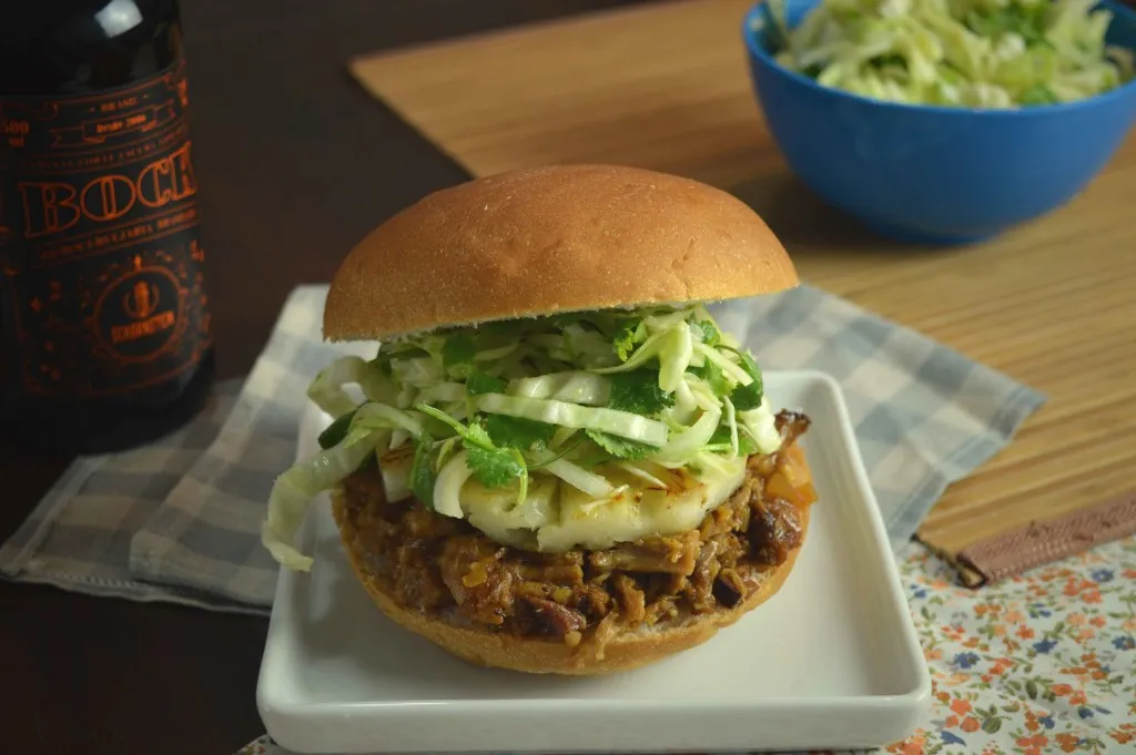 Sanduíche de pernil desfiado com queijo e salada de repolho ao lado de garrafa de Bock Schornstein