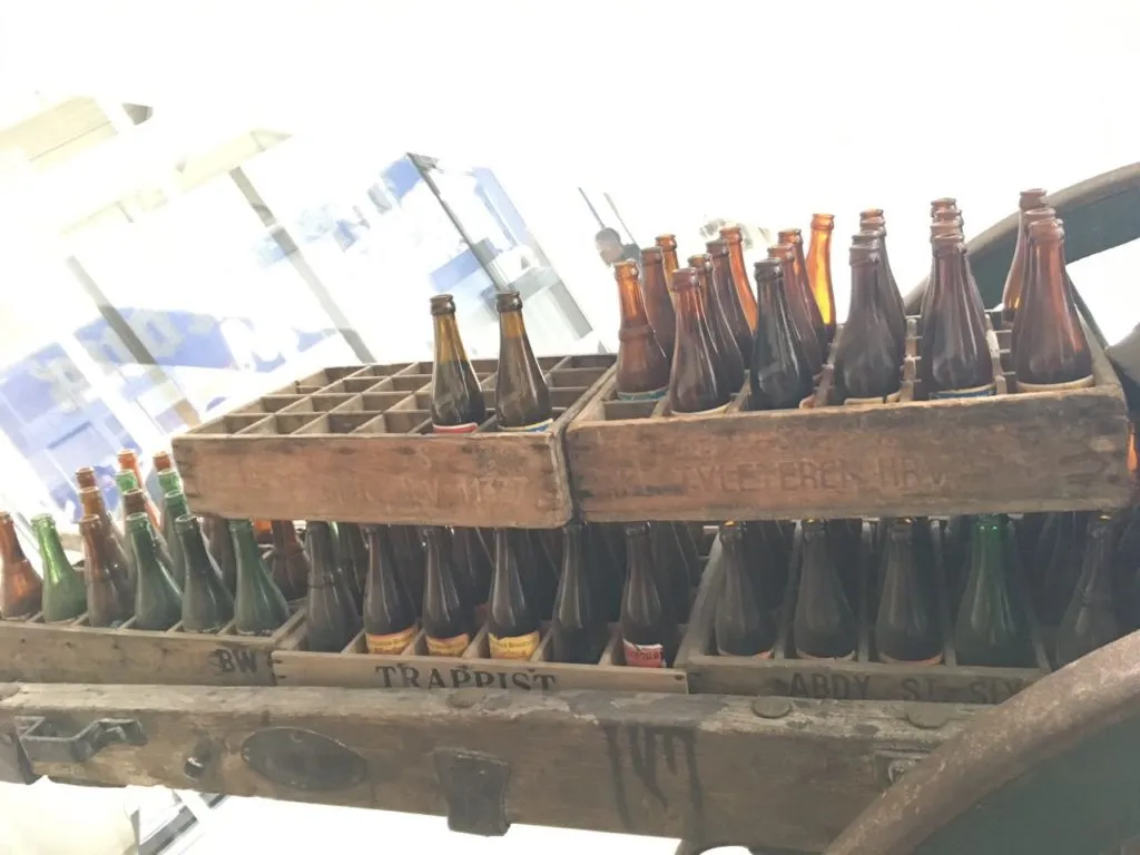 Engradados de madeira antigos com garrafas de cerveja, entre eles um marcado Trappist
