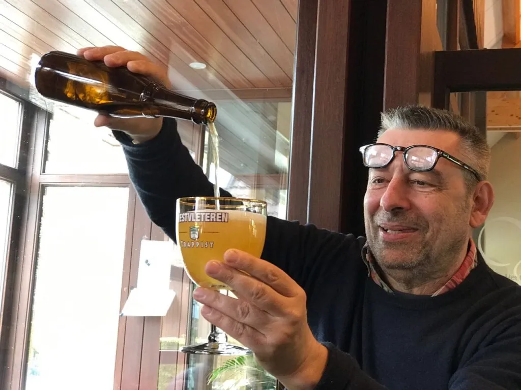 Homem servindo cerveja dourada de garrafa em taça Westvleteren Trappist