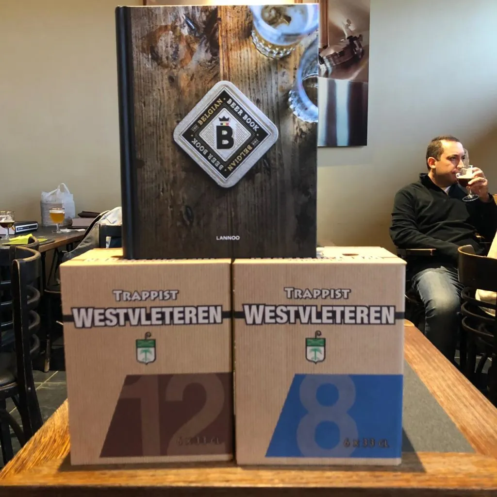 Caixas de cerveja Westvleteren 12 e 8 empilhadas sob o livro The Belgian Beer Book